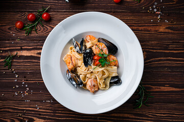 Linguini pasta with mussels, shrimps, cherry tomatoes, sauce and herbs, dinner.