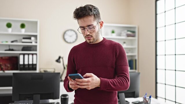 Young hispanic man business worker talking on smartphone working at office