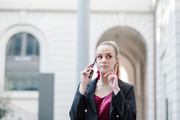 Portrait of a happy woman walking and talking on phone in the street