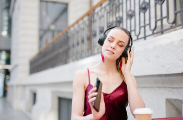 Smiling woman listening to music with her headphones in coffee shop