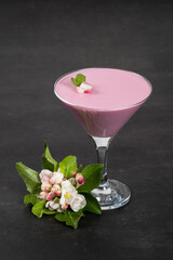 Pink tea matcha Panna Cotta in martini glass. Creamy Panna Cotta dessert with the addition of pink pitahaya powder. Dark gray background. Copy space
