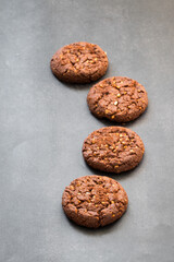 Vegan Cocoa oatmeal cookies with crushed peanuts. Dark gray background