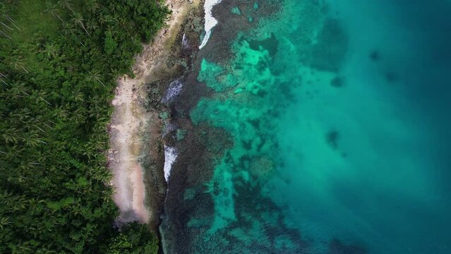 Aerial drone footage of mainly Recife in Philippines. Beautiful view of a mini bay with jungle beach recife and waves. Film movement is a zoom out.