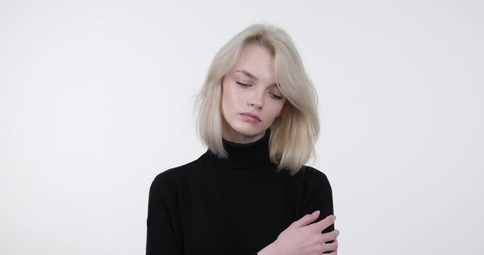 Caucasian woman standing against a white background, exuding an air of sorrow and isolation. With a downcast expression and a hint of vulnerability in her eyes, she captures the essence of loneliness.