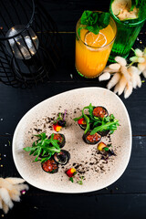 Rolled black pancakes with salmon, red caviar, spinach and arugula.