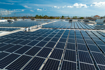 Aerial view of blue photovoltaic solar panels mounted on industrial building roof for producing...