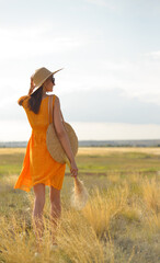 Beauty romantic girl outdoors. Rear view of a beautiful girl dressed in a casual orange dress with...