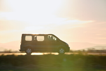 Passenger van driving fast on intercity road at sunset. Highway traffic in evening