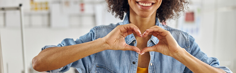 Smiling African-American fashion designer in denim shirt shows h