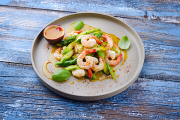 Grüner Spargel Salat gedämpft als Spitzen und Scheiben mit Garnelen und Passionsfrucht Vinaigrette serviert als Draufsicht auf einem Nordic Design Teller mit Textfreiraum