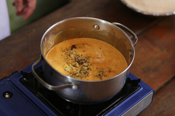 Panela borbulhante preparando o doce tradicional da culinária caiçara de Paraty: o Pé-de-Moleque. Feito com ingredientes autênticos como farinha de mandioca, gengibre ralado e melado de cana.