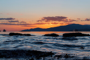 Obraz premium Dramatic sunset over mountains with ocean water in the front