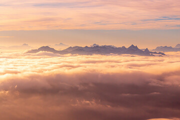 Fototapeta na wymiar Orange sunset with mountain peaks above clouds