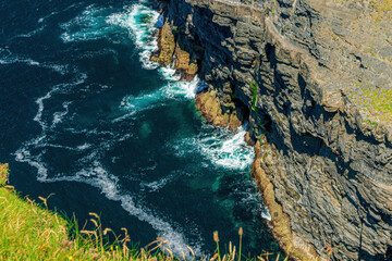 Ocean waves crashing into a high rock cliff