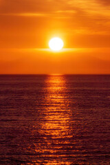 Fototapeta na wymiar Orange sunset with ocean and a neverending horizon