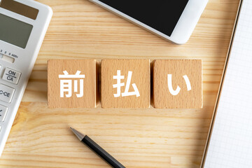 前払いと書かれたブロック、電卓、スマホ、ノート