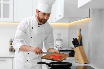 Professional chef putting cut tomatoes into frying pan in kitchen