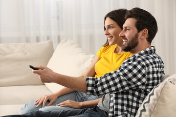 Happy couple watching TV on sofa at home
