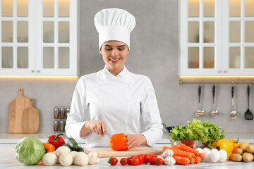 Professional chef cutting cut bell pepper at white marble table in kitchen
