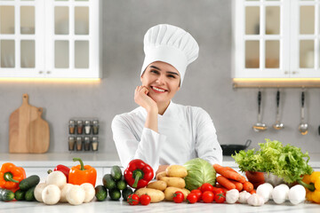 Portrait of happy chef near fresh vegetables in kitchen