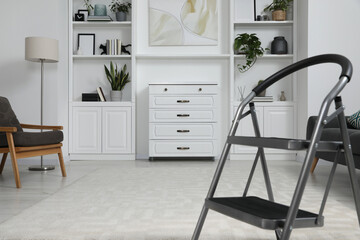 Fototapeta na wymiar Metal folding ladder on soft carpet in stylish room