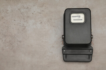Black electric meter on grey background, top view with space for text. Measuring device