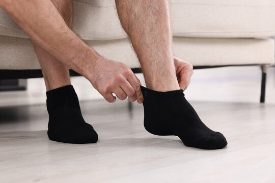 Man putting on black socks at home, closeup
