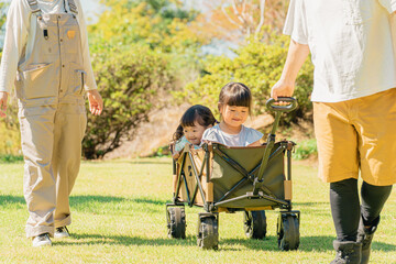 アウトドア・公園でキャリーワゴンに乗って遊ぶ子供（女の子・キャンプ）  © buritora