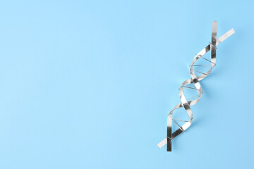 DNA molecular chain model made of metal on light blue background, top view. Space for text