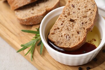 Bowl of organic balsamic vinegar with oil served with spices and bread slices on beige table, closeup