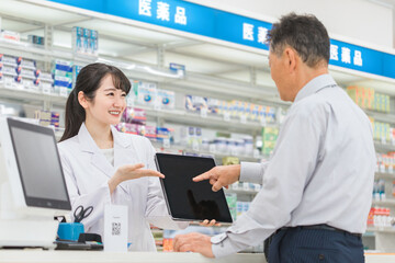 Fototapeta premium 薬局でタブレットPCを使いながら説明する薬剤師・調剤師（レセコン・レセプトコンピュータ） 