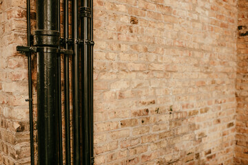 Old brick wall that has cracked and patched and old black pipes, background image