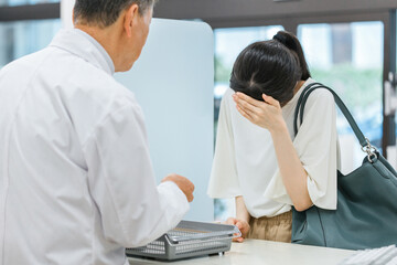 Obraz premium 薬局に来た体調不良の女性と薬剤師 