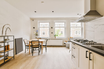 a kitchen and dining area in a small apartment with white walls, wood flooring and marble countertops on either side