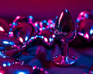 Lots of metal anal plugs in neon pink purple light. 