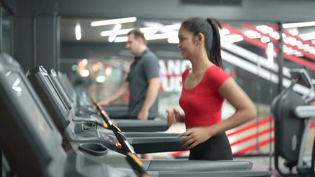 Beautiful Asian woman exercising on treadmill in gym.