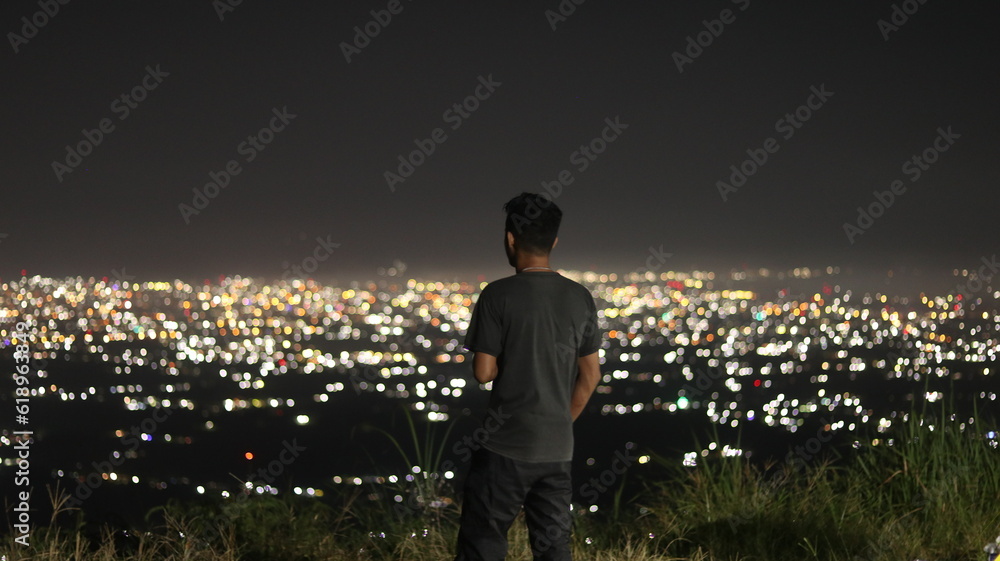 Wall mural the man stand on the background of the city lights. night time