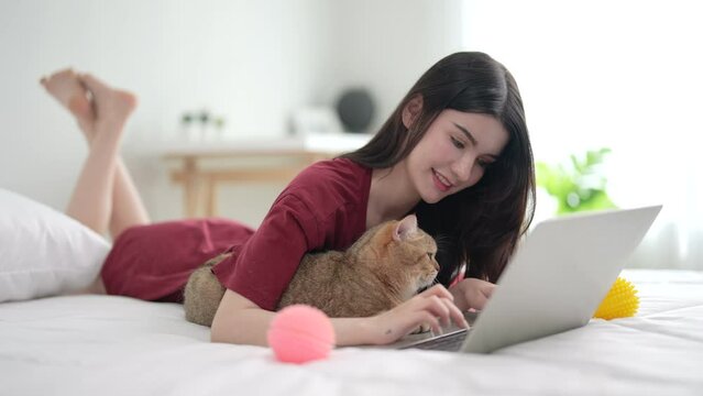 Cheerful woman in casual clothes spending her free time on vacation playing with cute pet at home.