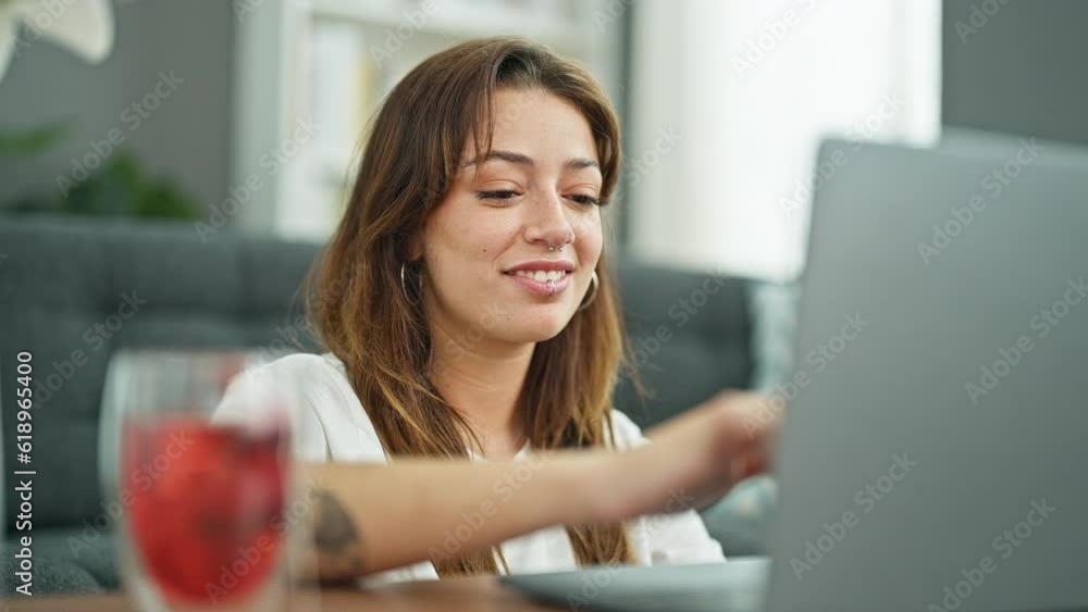 Sticker Young beautiful hispanic woman closing laptop stretching arms at home