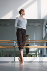 elegance woman, professional ballerina standing on pointe shoes in choreography class near barre