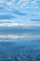 Naklejka na ściany i meble Nature picturesque landscape, clouds reflected on water surface, windless summer weather, tranquil blue trend sky background, mirroring sky on water, white blue nature gradient, aesthetic