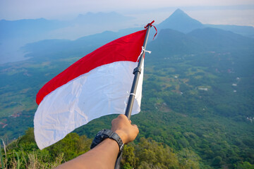 hand holding Indonesia flag on blue sky background with nature view Indonesia independence day,...
