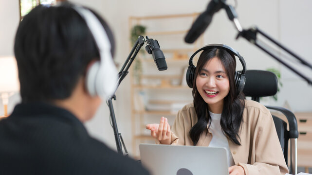 Young women using laptop and microphone to interviewing man guest and recording for audio podcast