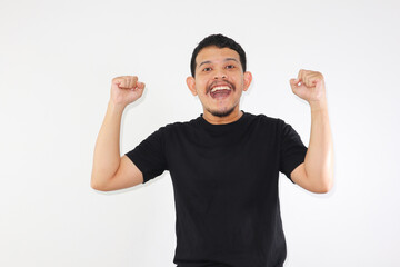 Fototapeta premium Very happy young asian man victor. clenched hands and raised, isolated in gray background.