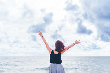 Fototapeta na wymiar Young woman rise hand up to sky on summer beach background feel relax and energize.