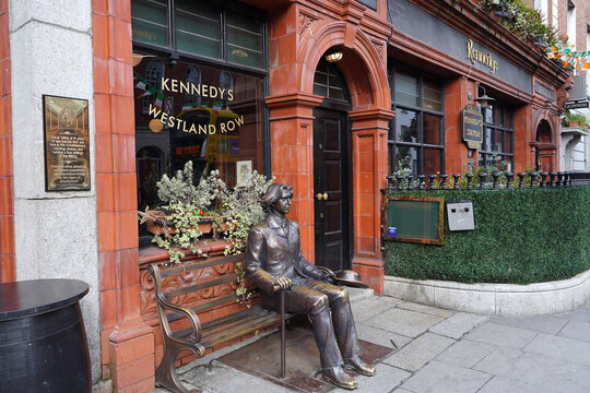 Statue of Oscar Wilde sitting on a bench outside a pub where he worked as a teenager