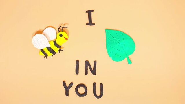 Plasticine stop motion animation. Funny comic phrase i bee leaf in you on the background of a plasticine bee and green leaves. Claymotion