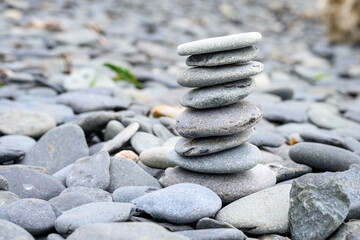 Calming stack of flat round stones on a rocky beach, ready for meditation, zen background
