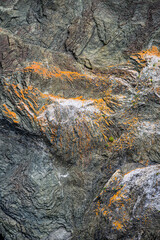 Interesting geologic feature in rock layers with colorful lichen, patterns and texture in nature, as a nature background
