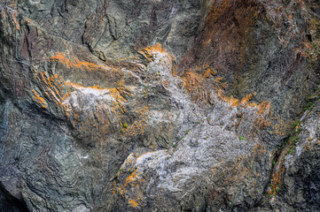 Interesting geologic feature in rock layers with colorful lichen, patterns and texture in nature, as a nature background
